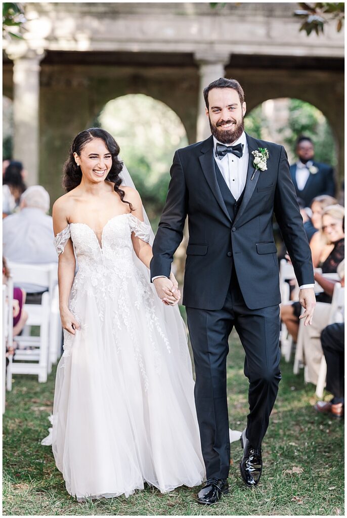 The bride and groom walk down the aisle as husband and wife, beaming with bright smiles at their Virginia House wedding ceremony in Richmond in the fall. Photo by a Richmond wedding photographer, Emily Nicole Photography.