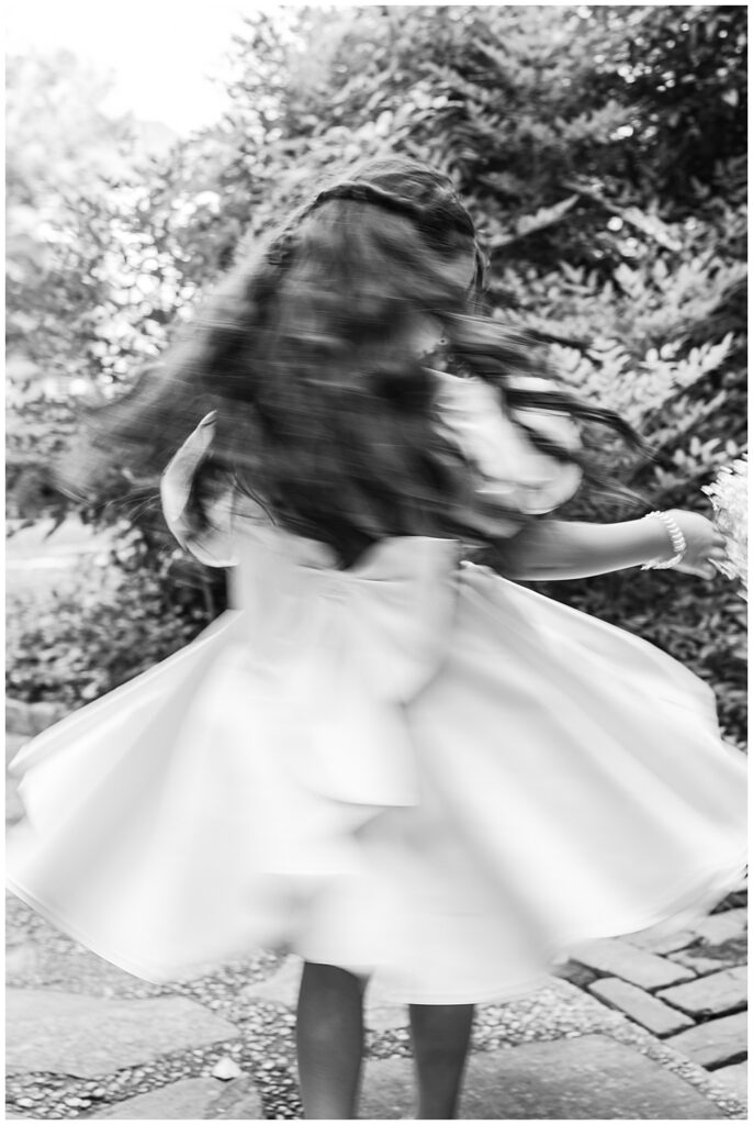A flower girl twirls for a portrait at Virginia House in Richmond, serving as the enchanting, fairytale estate wedding venue. Photos by a Richmond wedding Photographer, Emily Nicole Photography.