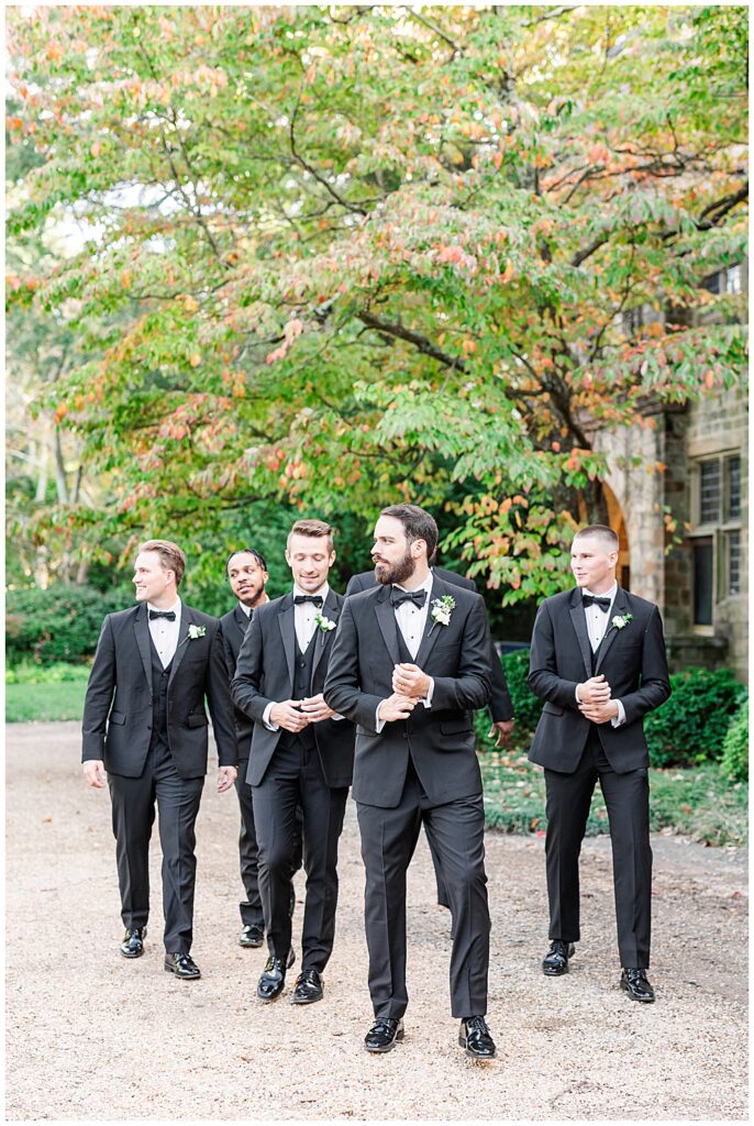 A groom and his black-tie attired groomsmen pose for portraits at Virginia House in Richmond, serving as the enchanting, fairytale estate wedding venue. Photos by a Richmond wedding Photographer, Emily Nicole Photography.