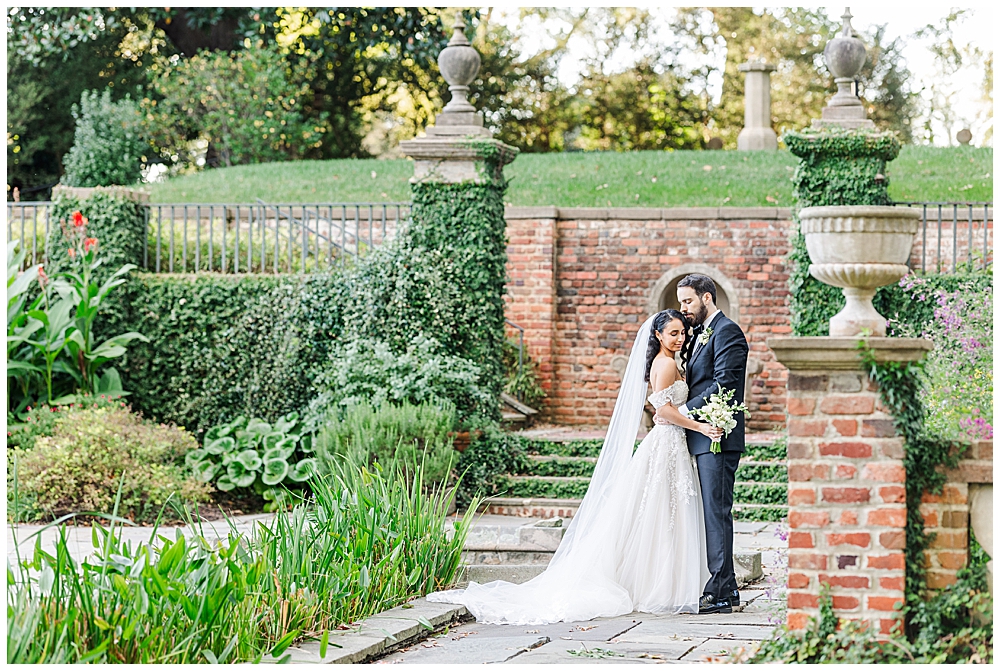 A bride and groom pose in one of the sunken Tudor-style gardens of the Virginia House in Richmond, serving as their enchanting, fairytale estate wedding venue. Photos by a Richmond wedding Photographer, Emily Nicole Photography.