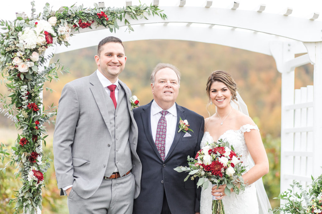 breaux vineyard, bride and groom with minister, pastor, officiant, under wedding arbor, fall wedding, fall florals, burgundy wedding, wine wedding