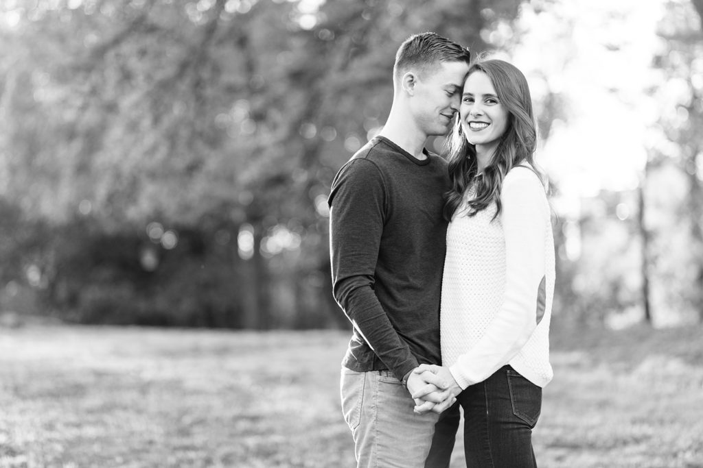 Black and white couple portrait. Lee leans in to nuzzle against Danielle's forehead while she smiles at the camera during their fall session.