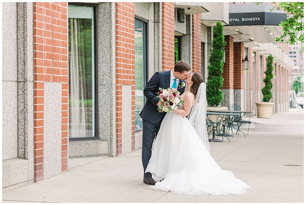 A bride and groom kiss in front of the Royal Sonesta hotel in Baltimore, MD