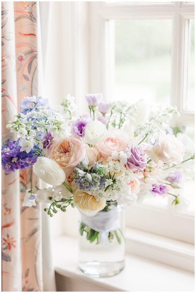 Dreamy pastel-themed wedding colors for spring. A free-flowing bridal bouquet with mixed florals of roses, tulips, ranunculus, astilbe, sweet peas, and more!