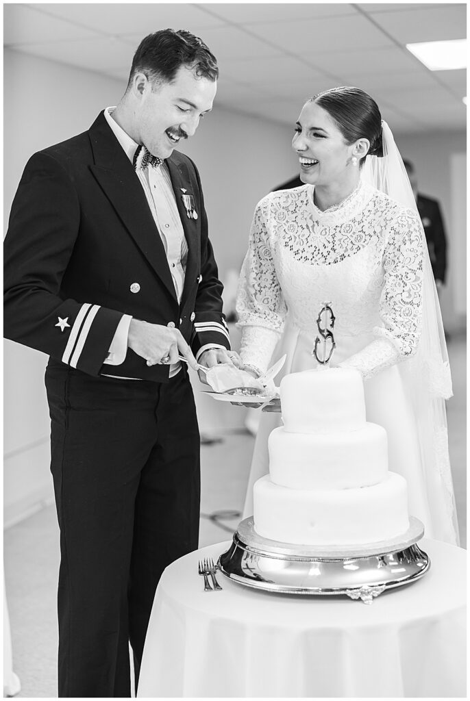Navy servicemember groom and his bride cut the cake after their traditional Catholic wedding ceremony at Basilica School of Saint Mary in Washington, D.C. | Photo taken by D.C. wedding photographer