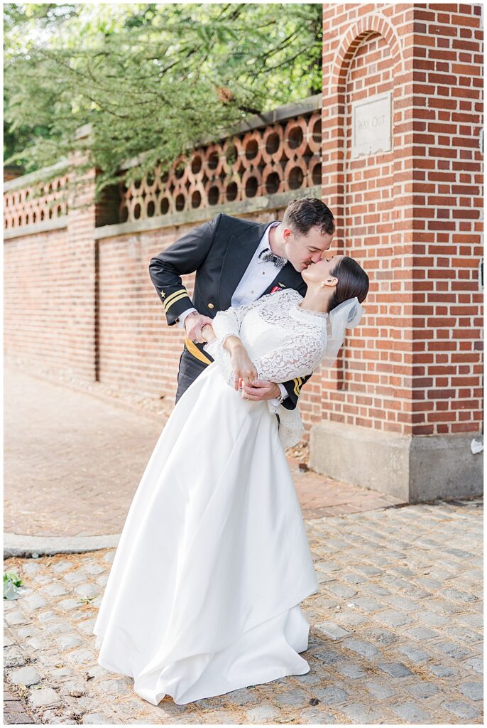 Military groom and his bride share a kiss in front of the Dumbarton Oaks Museum gate in Georgetown, taken after their traditional Catholic wedding ceremony at Basilica School of Saint Mary in Washington, D.C. | Photo taken by D.C. wedding photographer