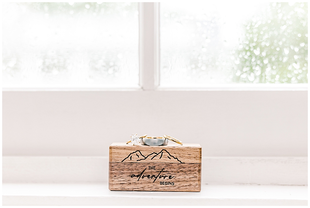 Wedding rings ontop of a wooden ring box, against a rainy window pane | Northern VA Wedding Photographer