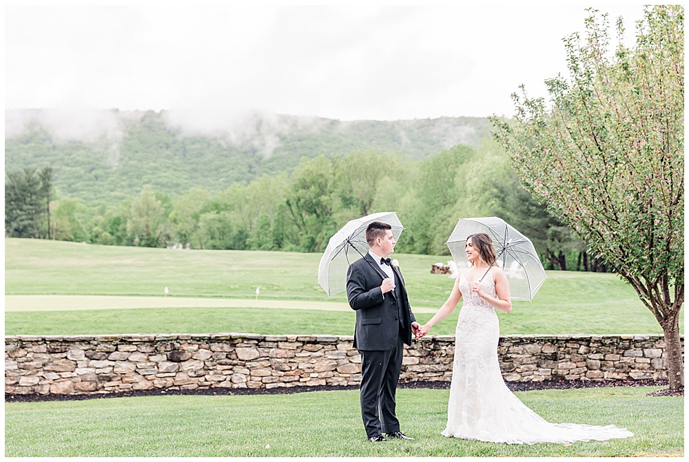 Rainy wedding photos of bride and groom holding clear umbrellas at their Evergreen Country Club wedding | Northern VA wedding photographer