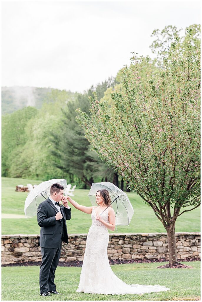 Romantic rainy wedding photos of bride and groom holding clear umbrellas at their Evergreen Country Club wedding | Northern VA wedding photographer