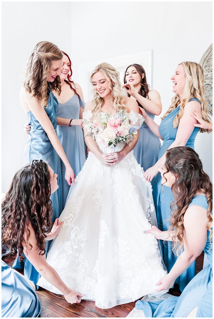 Bridesmaids wearing sky blue dresses help fluff bride's dress before wedding ceremony | Fairytale-themed Historic Mankin Mansion wedding in June | Richmond wedding photographer