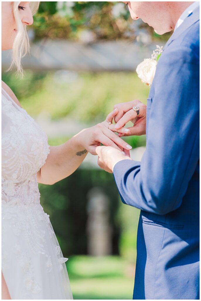 Groom places wedding band on the bride's finger during their outdoor summer wedding ceremony

River Farm Wedding | Alexandria Wedding Photographer