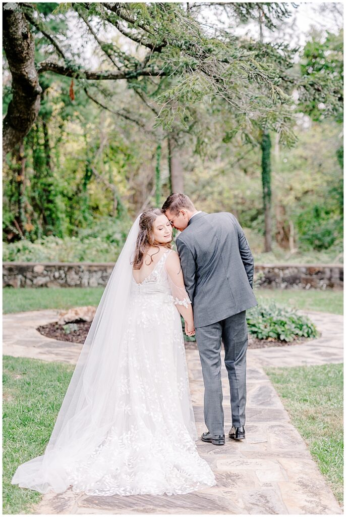 A full-length shot of a bride and groom resting forehead-to-forehead for a photo. The bride's long veil and train are fanned out behind them. 

Rust Manor House Wedding | Leesburg Wedding Photography | VA Wedding Venues